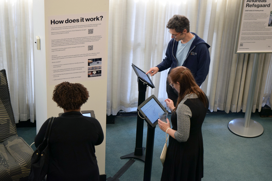 Three people interacting with a tablet at an exhibit.
